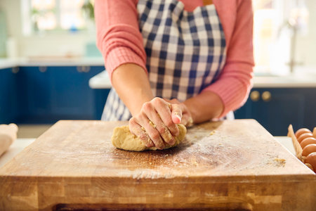 Close Up Of Woman At Home In Kitchen Making Dough On Worktop Or Counterの写真素材