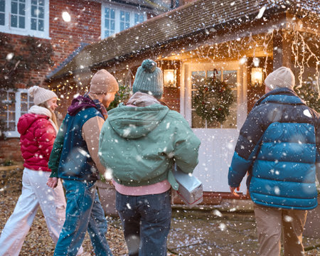 Group Of Smiling Teenage Friends Outdoors Dressed For Winter In Snow Delivering Christmas Presentsの写真素材
