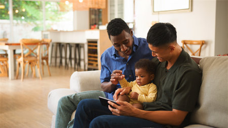 Two men and a baby engage with a tablet in a bright, welcoming home environment.
