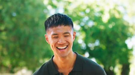 A man smiles widely while enjoying a sunny day outdoors.の写真素材