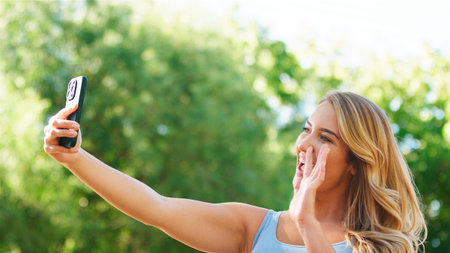 Woman enjoying a sunny day while capturing a selfie in the park.