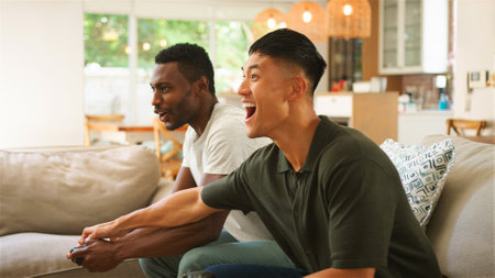 Friends cheer and enjoy gaming together in a warm, inviting space.の写真素材