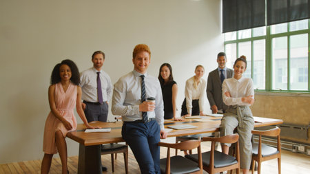 Portrait Of Multi-Cultural Business Team Standing Around Table In Modern Office After Meeting