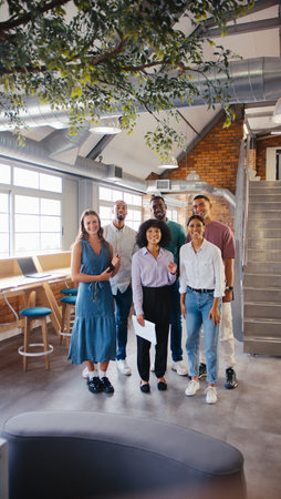 Portrait Of Multi-Cultural Business Team Standing In Modern Open Plan Office Together