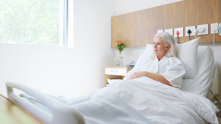 Mature Female Patient Lying In Private Hospital Bedの写真素材