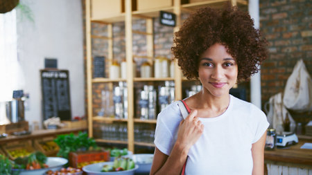 Portrait Of Smiling Young Woman With Reusable Bag Shopping In Sustainable Plastic Free Grocery Storeの写真素材
