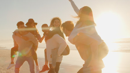 Group Of Young Friends Having Piggyback Race On Winter Beach Together With Lens Flare
