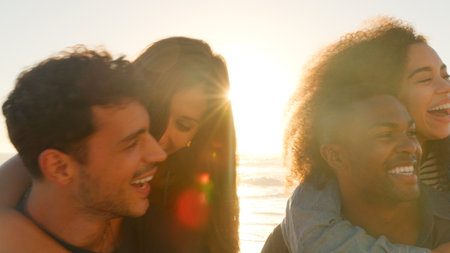 Close Up Of Group Of Young Friends Having Piggyback Race On Winter Beach Together With Lens Flare