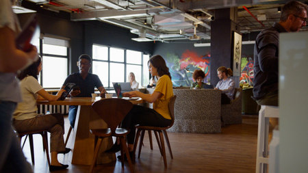 Informal Meeting Area In Modern Office With Businesspeople Meeting And Working At Tables