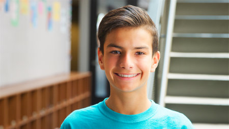 Portrait Of Smiling Male High School Student Standing By Stairs In College Building