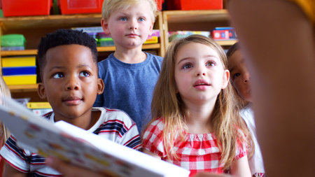 Close Up Of Elementary School Pupils Sitting On Floor Listening To Female Teacher Read Storyの写真素材