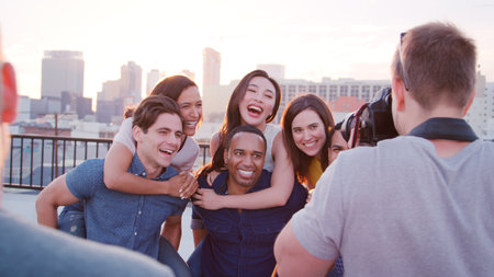Male Photographer Photographing Group Of Friends Against Los Angeles Skyline At Sunset