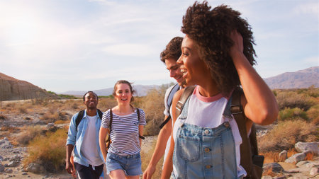 Multi-Cultural Group Of Friends Wearing Backpacks Hiking Through Countryside Togetherの写真素材