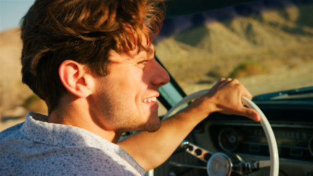 Close Up Of Man Driving Classic Open Top Car On Road Trip Through Countryside At Sunsetの写真素材