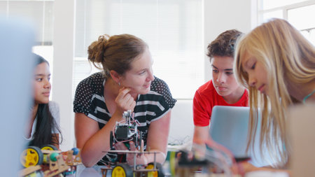 Students With Female Teacher In School Computer Class Building And Programming Robot Vehicle
