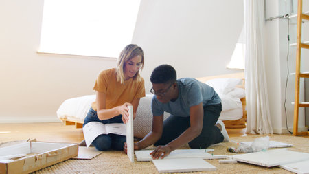 Young Couple In New Home Sitting On Floor Putting Together Self Assembly Furniture
