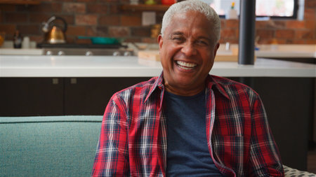 Portrait Of Smiling Senior Man Relaxing On Sofa At Home