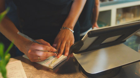 Close Up Of Waitress Totalling Bill At Coffee Shop Checkoutの写真素材