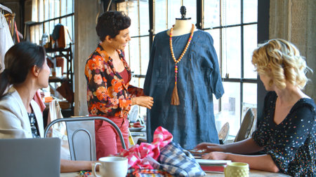 Three Female Fashion Designers In Studio Meeting Discussing Garment On Dummy