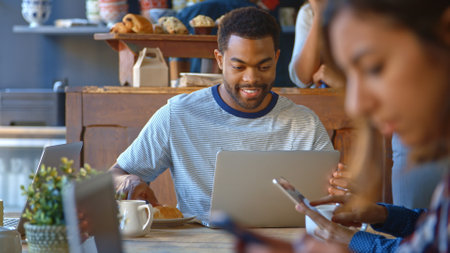 Male Customer In Coffee Shop Sitting At Table Using Laptop Computer