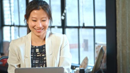 Female Fashion Designer In Creative Industry Sitting At Desk Using Laptop In Studioの写真素材