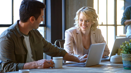 Two Businesspeople Sitting At Table Working At Laptops In Coffee Shopの写真素材