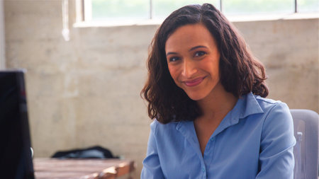 Head And Shoulders Portrait Of Businesswoman Sitting At Desk In Office Working On Computerの写真素材