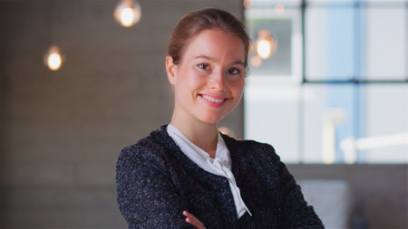 Head And Shoulders Portrait Of Smiling Confident Businesswoman Standing By Window In Modern Office