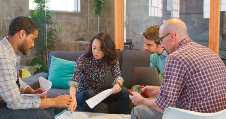 Group Of Creative Businesspeople Having Informal Meeting Around Seating Area In Modern Officeの写真素材