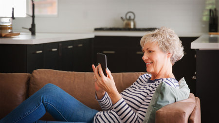 Senior Woman On Sofa At Home Using Mobile Phone Browsing Online Streaming Show Or Checking Messages
