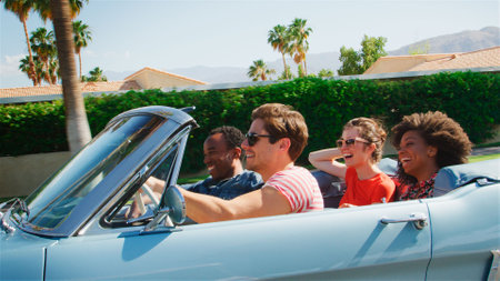 Side View Of Group Of Young Friends On Road Trip Driving In Classic Convertible Carの写真素材
