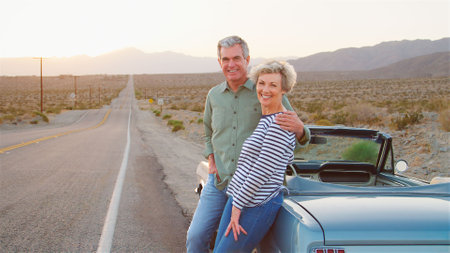 Portrait Of Senior Couple On Road Trip Standing By Classic Convertible Car On Country Roadの写真素材