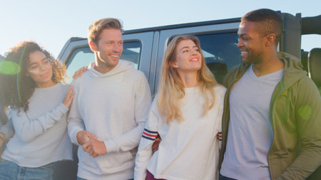 Group Of Young Friends On Road Trip Standing Next To Convertible Car