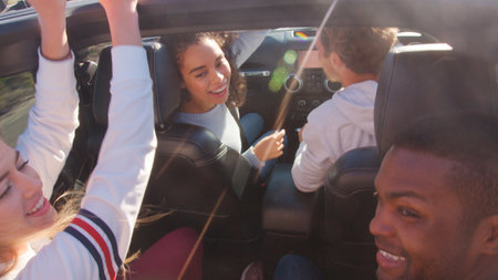 Close Up Of Group Of Young Friends On Road Trip Driving In Convertible Carの写真素材