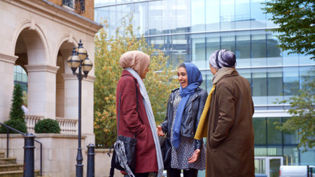 Group Of Young British Muslim Businesswomen Meeting And Talking Outside Office