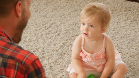 Father Sitting On Floor With Young Daughter Playing With Colourful Plastic Toys At Homeの写真素材