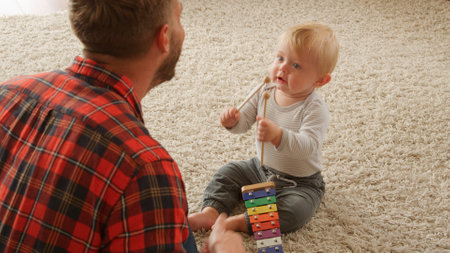 Father And Baby Son Playing Music On Toy Xylophone At Home Togetherの写真素材