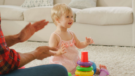 Father Sits With Young Daughter At Home Playing With Plastic Stacking Toys