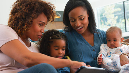 Multi-Generation Female African American Family Sitting On Sofa At Home Watching TV Together