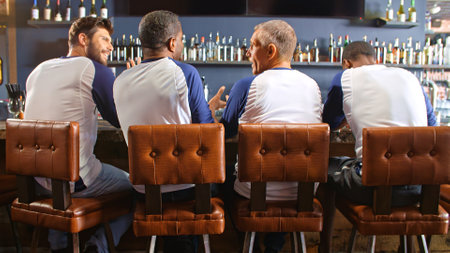 Rear View Of Male Friends Wearing Team Colours Watching Game In Sports Barの写真素材