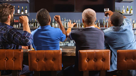 Rear View Of Male Friends Watching Game In Sports Bar