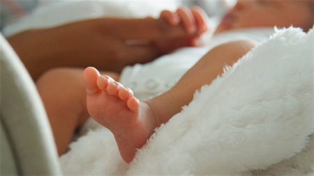 Close Up Of Feet Of Sleeping Newborn Baby Holding Parent's Finger In Nursery At Homeの写真素材