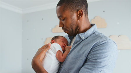 Loving Father Holding Newborn Baby Son In Nursery At Home