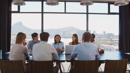 View Through Door Of Businessman Team Using Laptops Having Meeting Sitting Around Boardroom Tableの写真素材