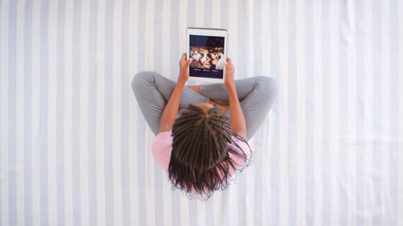 Overhead View Of Girl Looking At Digital Tablet On Bedの写真素材