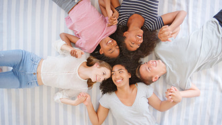Overhead View Of Teenage Friends Lying On Bed Together