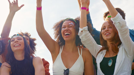 Group Of Female Friends In Audience Behind Barrier Dancing And Singing At Festival Enjoying Musicの写真素材