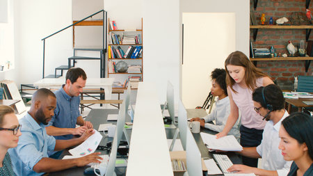Multi-Cultural Business Team Working At Desks On Computers In Modern Open Plan Office