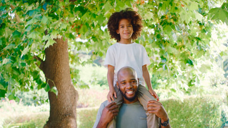 Portrait Of Father And Son In Summer Garden With Boy Riding On Dads Shouldersの写真素材