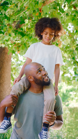 Father And Son In Summer Garden With Boy Riding On Dads Shouldersの写真素材
